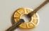Gold personalized jewel medallion engraved with zodiac signs, tied on a black cord bracelet